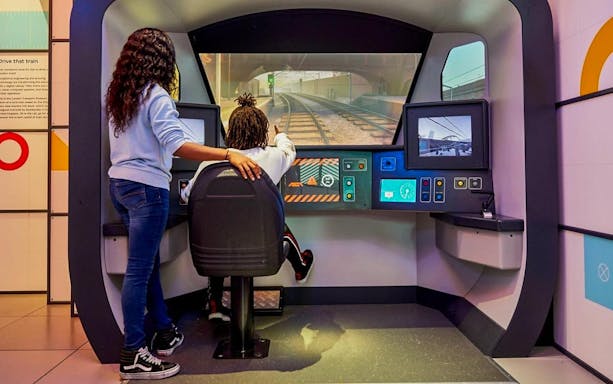 Visitors interact with a train simulator at the London Transport Museum.