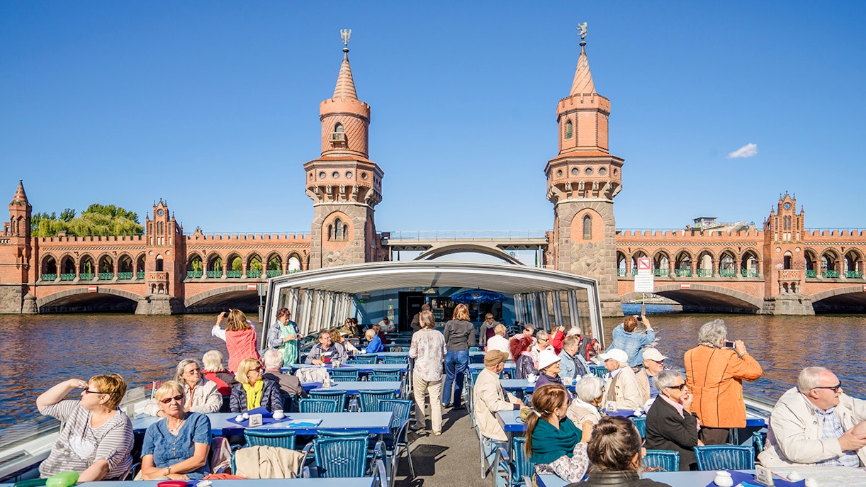 Guests on a boat tour viewing the Oberbaum Bridge in Berlin.