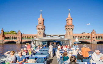 Guests on a boat tour viewing the Oberbaum Bridge in Berlin.