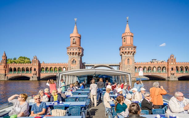 Guests on a boat tour viewing the Oberbaum Bridge in Berlin.