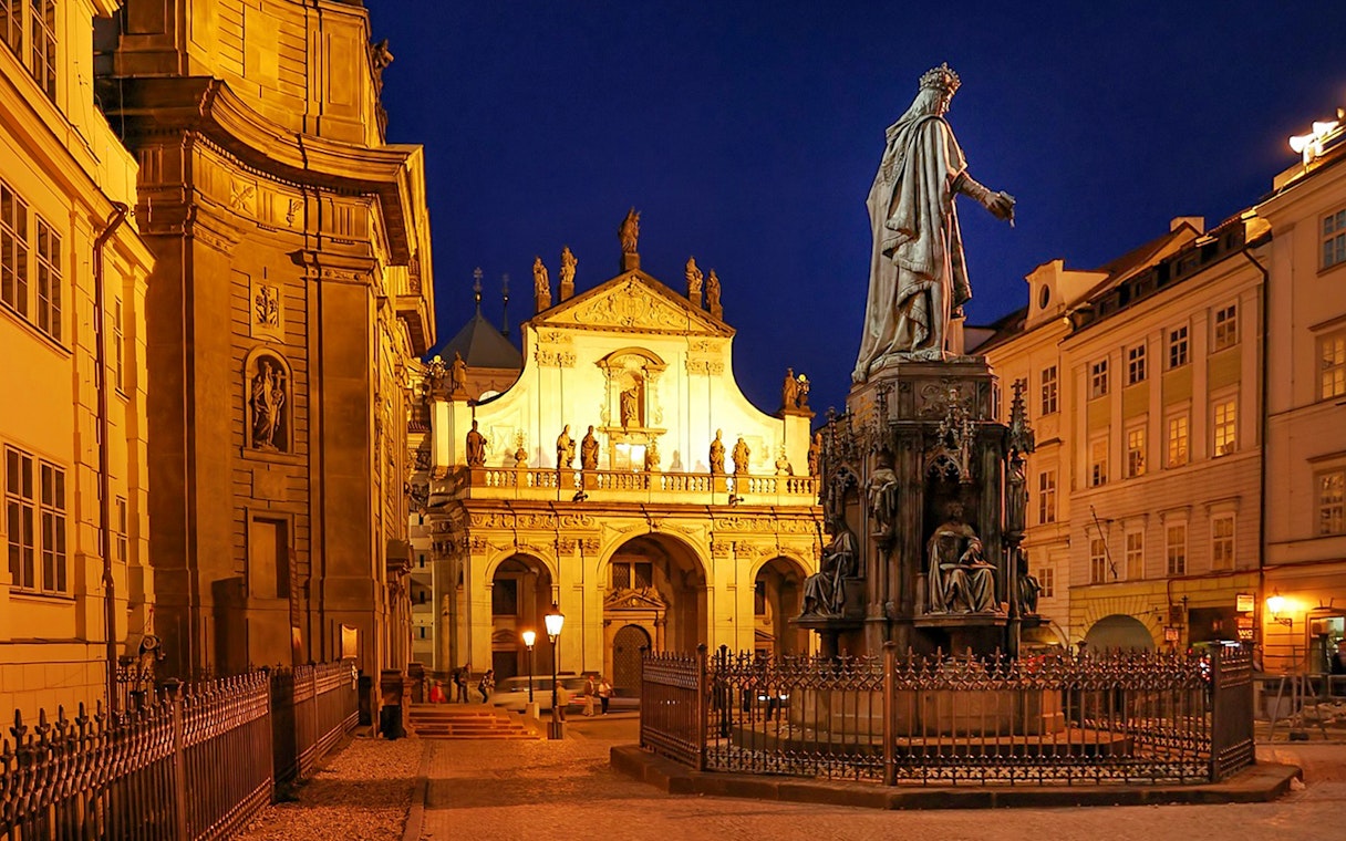 Medieval streets of Prague with illuminated statues and historic buildings at night.
