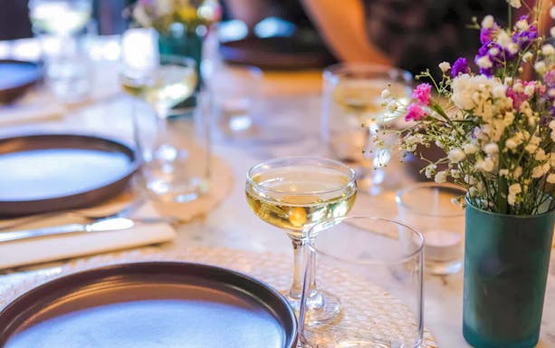 Champagne glass on a table with plates and flowers, Lisbon food tour.