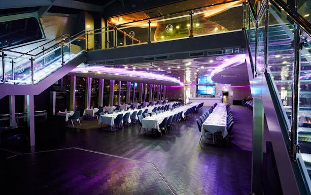 Elegant dining area on a Sydney dinner cruise ship with set tables and ambient lighting.