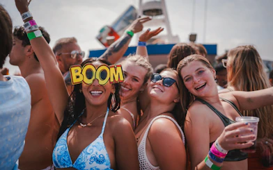 Tourists enjoying Cruise Crush Boat Party with drinks and festive atmosphere.