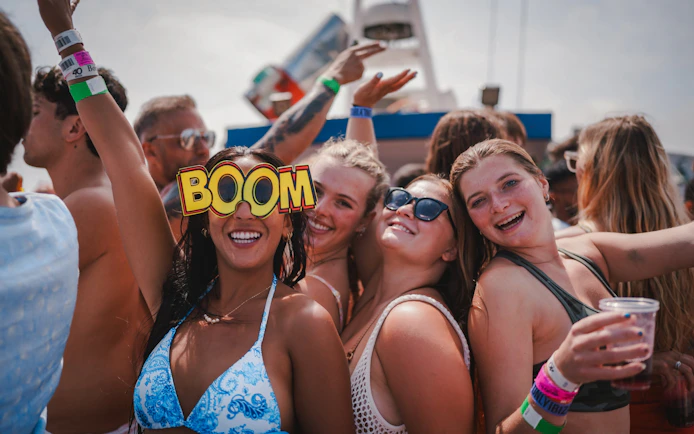 Tourists enjoying Cruise Crush Boat Party with drinks and festive atmosphere.