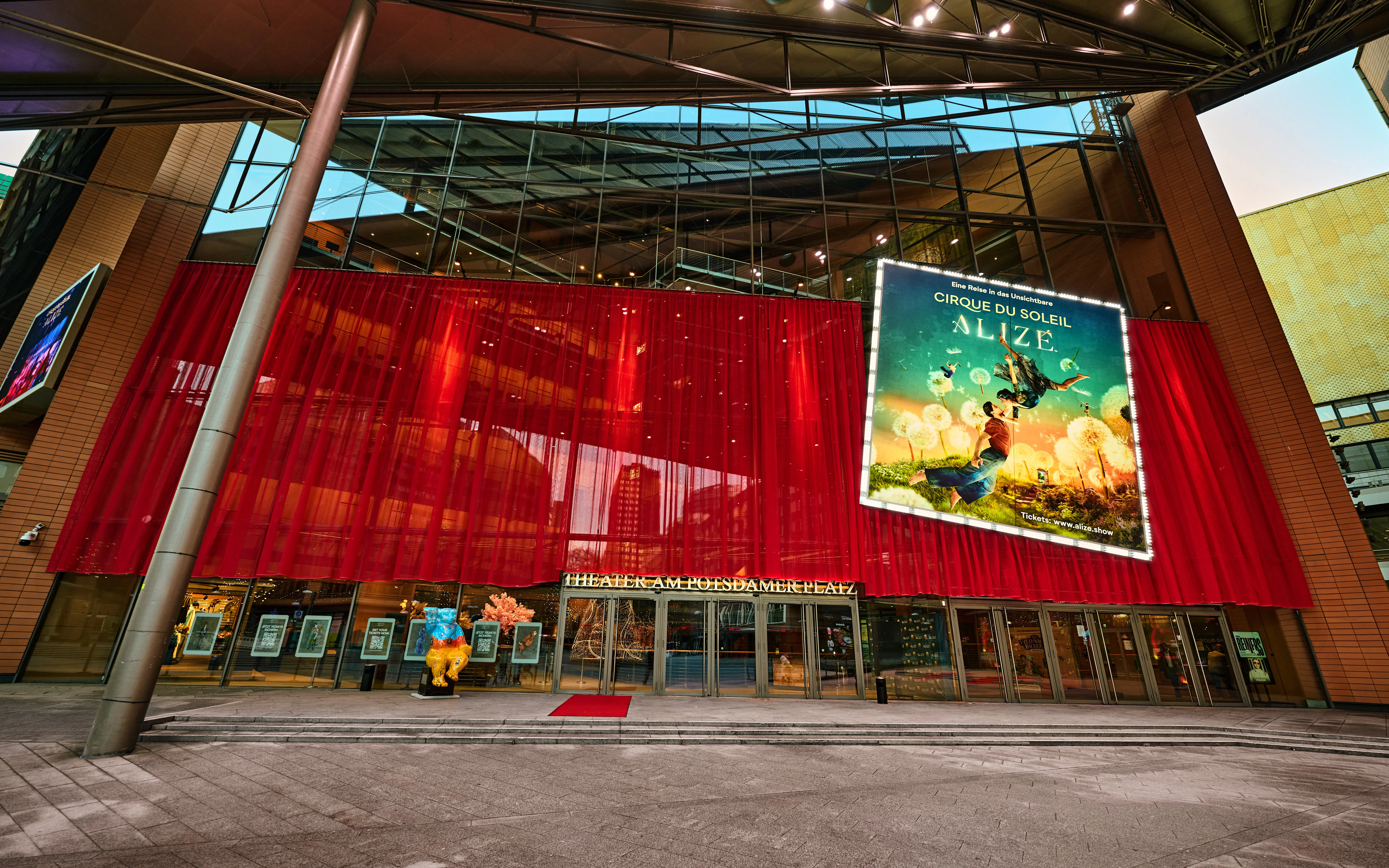 Exterior view of Cirque du Soleil Alizé Theatre with red drapes and promotional poster.