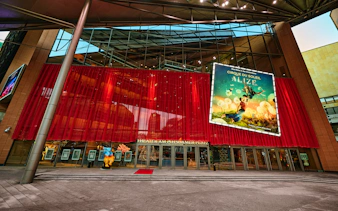 Exterior view of Cirque du Soleil Alizé Theatre with red drapes and promotional poster.