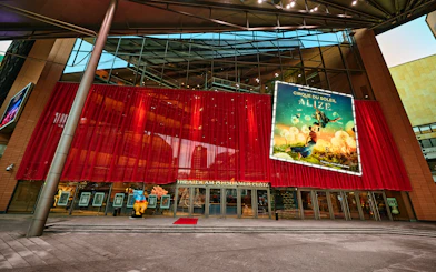 Exterior view of Cirque du Soleil Alizé Theatre with red drapes and promotional poster.