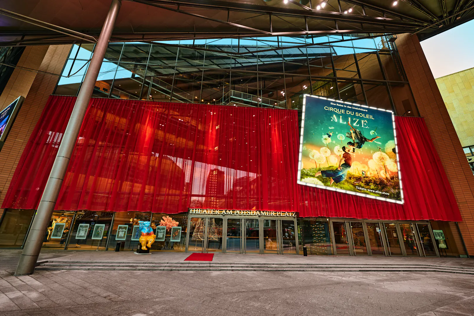 Exterior view of Cirque du Soleil Alizé Theatre with red drapes and promotional poster.