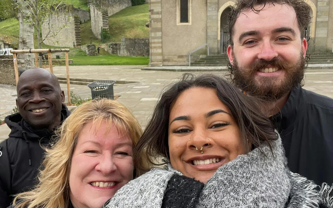 Group of people smiling in front of a historic building in Carcassonne during a self-guided city exploration game.