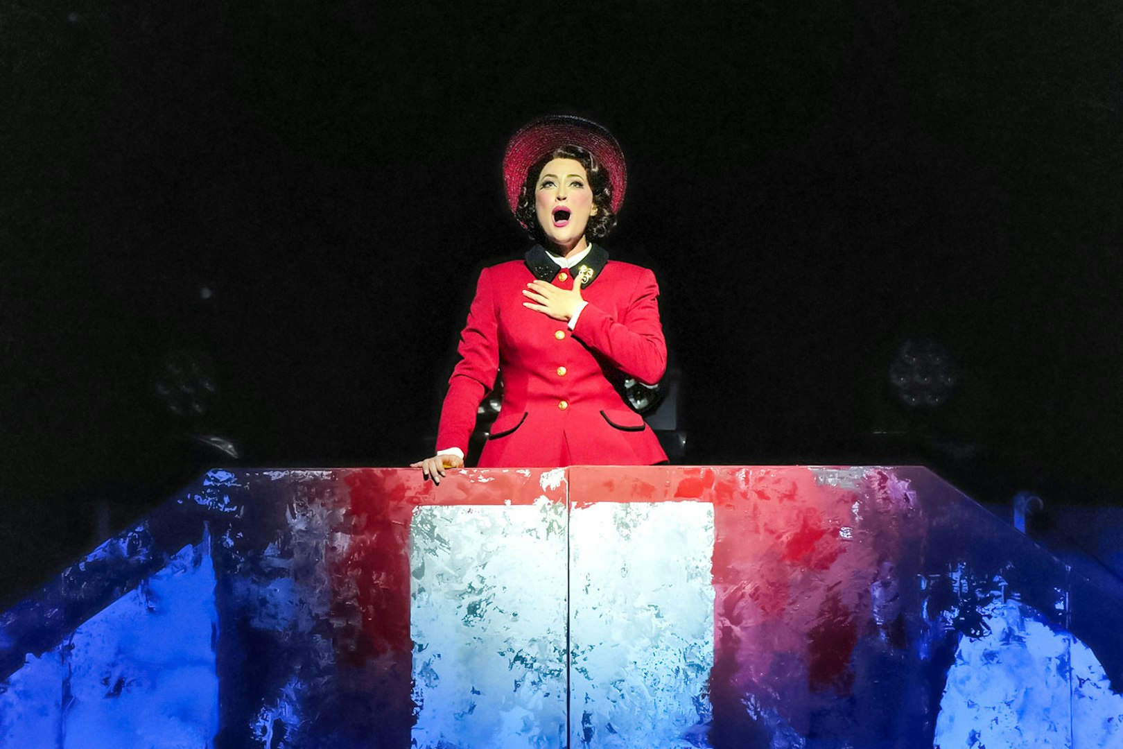 Performer in red costume singing in Guys & Dolls on Sydney Harbour stage.