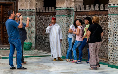 Visitors at Al Attarine Madrasa in Fes, Morocco, admire intricate tilework.