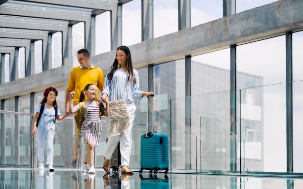 Family walking through airport terminal with luggage.