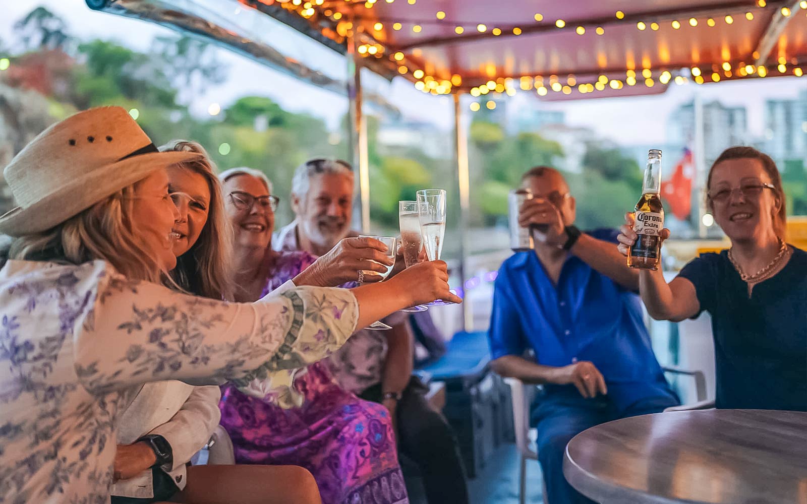 Friends toasting drinks on a Brisbane River cruise boat.