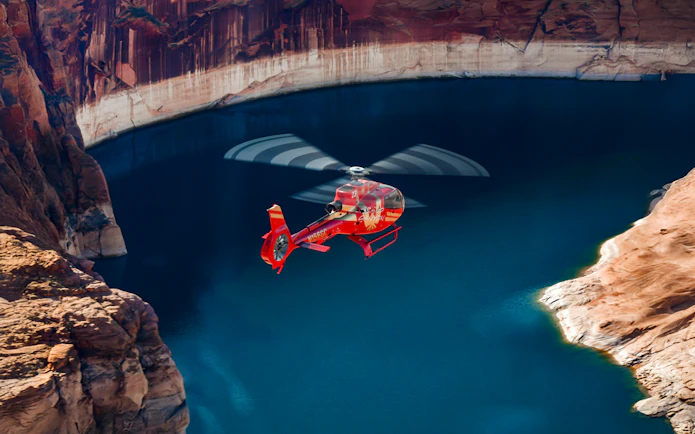 Red Papillon helicopter flying over Lake Powell's blue waters.