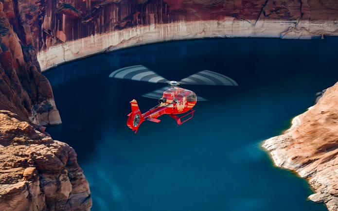 Red Papillon helicopter flying over Lake Powell's blue waters.