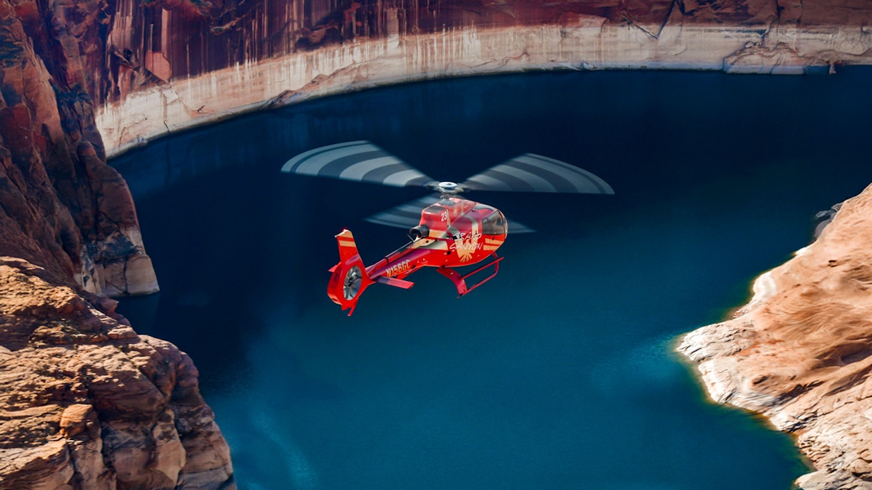 Red Papillon helicopter flying over Lake Powell's blue waters.