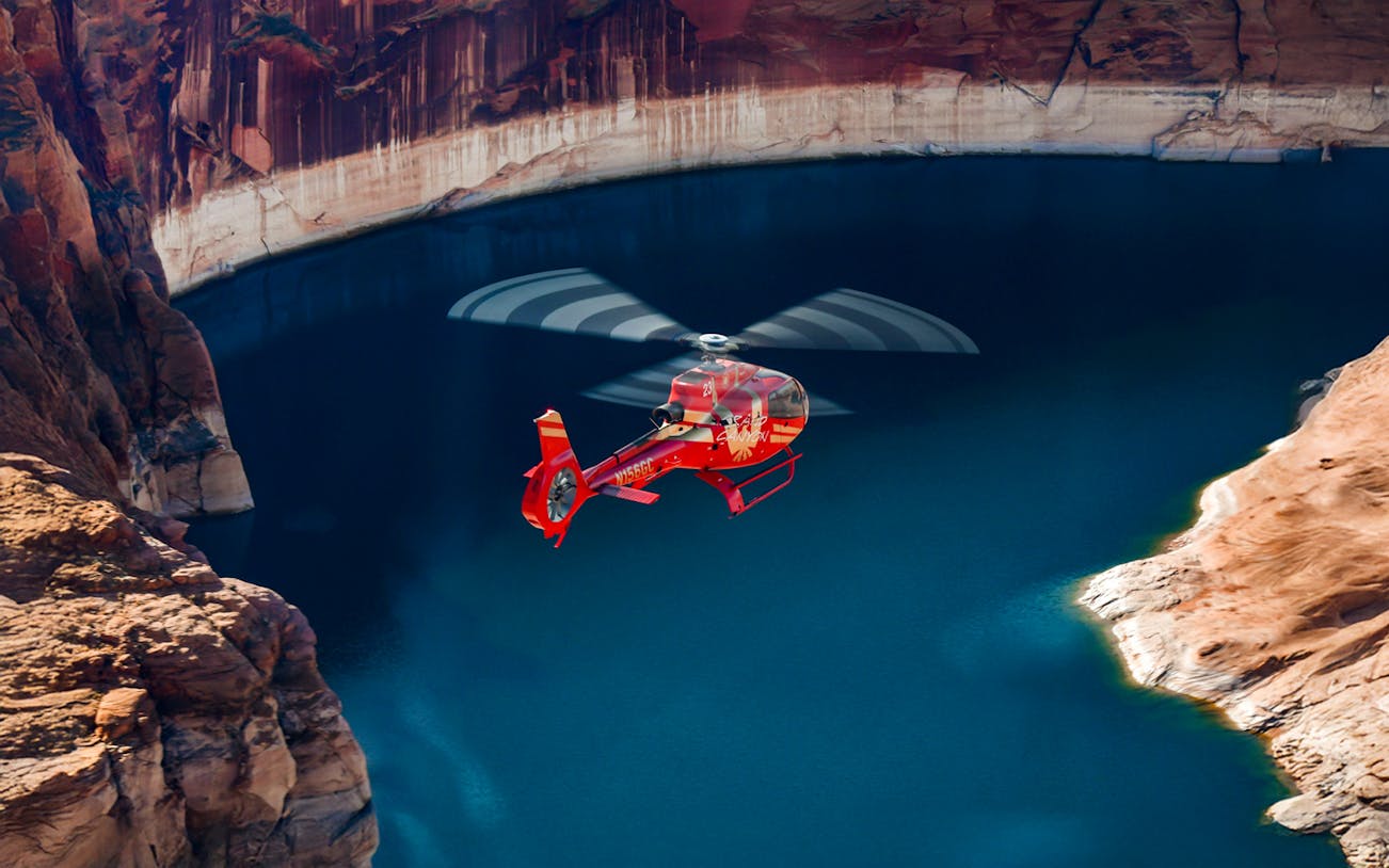 Red Papillon helicopter flying over Lake Powell's blue waters.