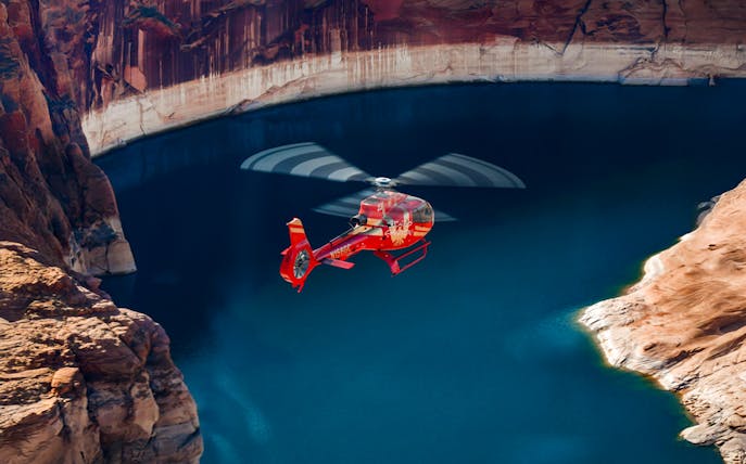 Red Papillon helicopter flying over Lake Powell's blue waters.