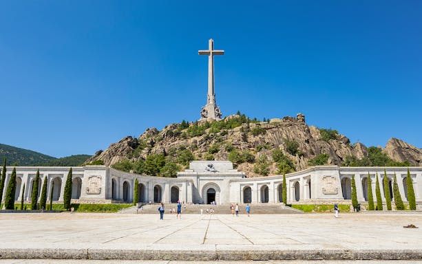 Valley of the Fallen monument with large cross and surrounding colonnade in Spain.