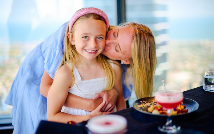 Mother and daughter enjoying dining at Melbourne Skydeck with city view.
