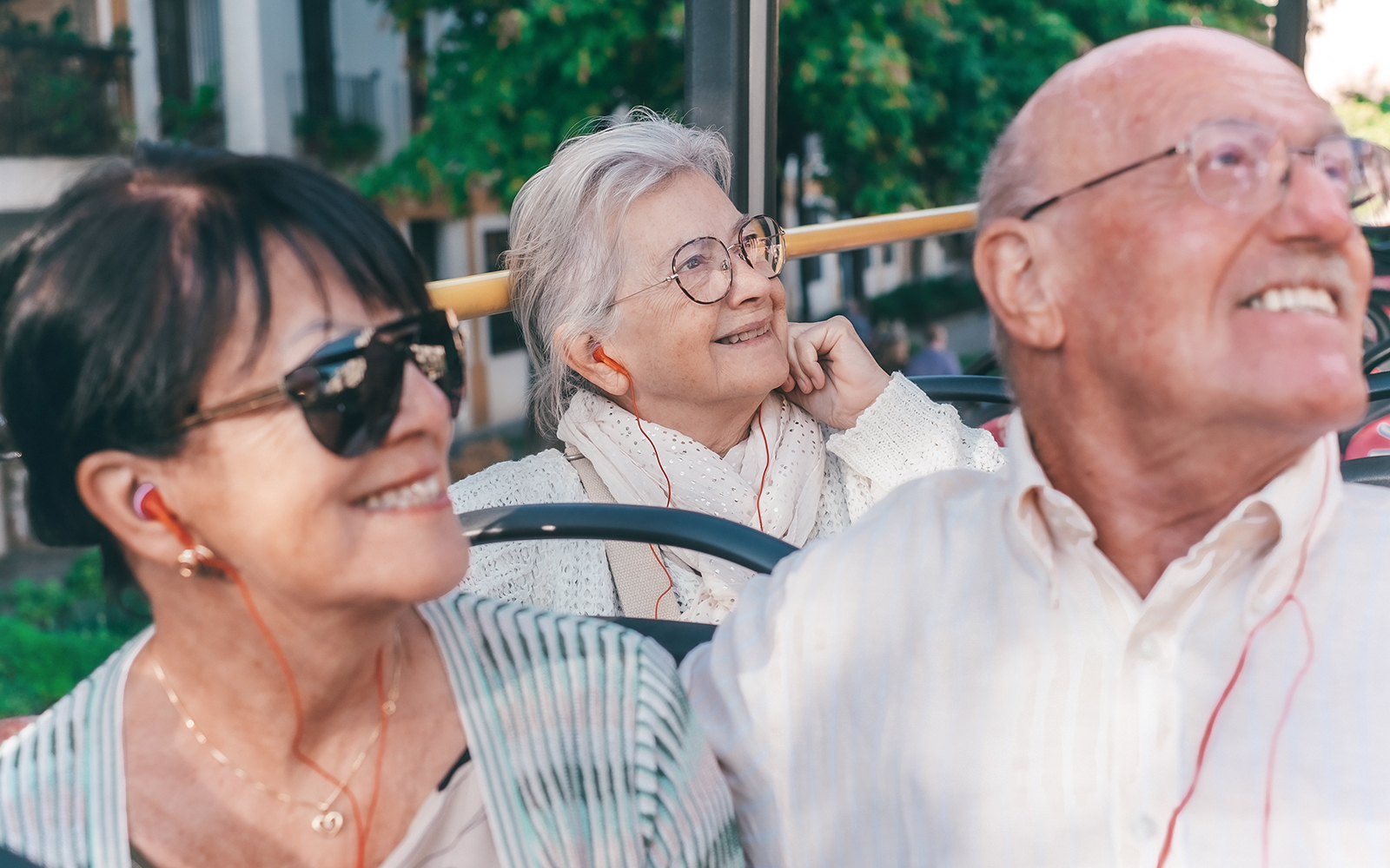 Smiling senior happy caucasian retired people sitting on sightseeing open-top bus visiting city