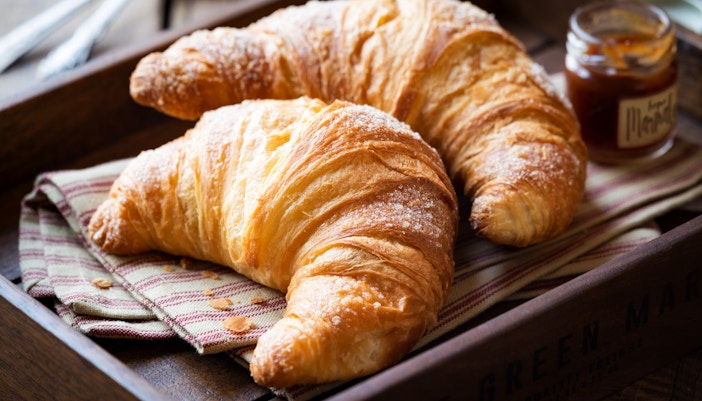 Freshly baked croissant on a wooden table in a Parisian café, France.