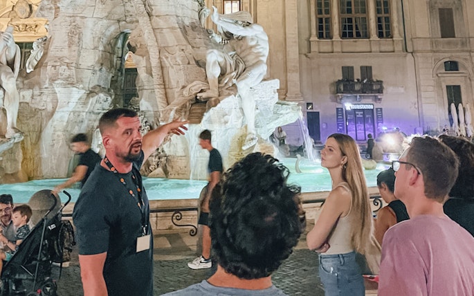 Tour guide explaining the Trevi Fountain to a group during a night walking tour in Rome.