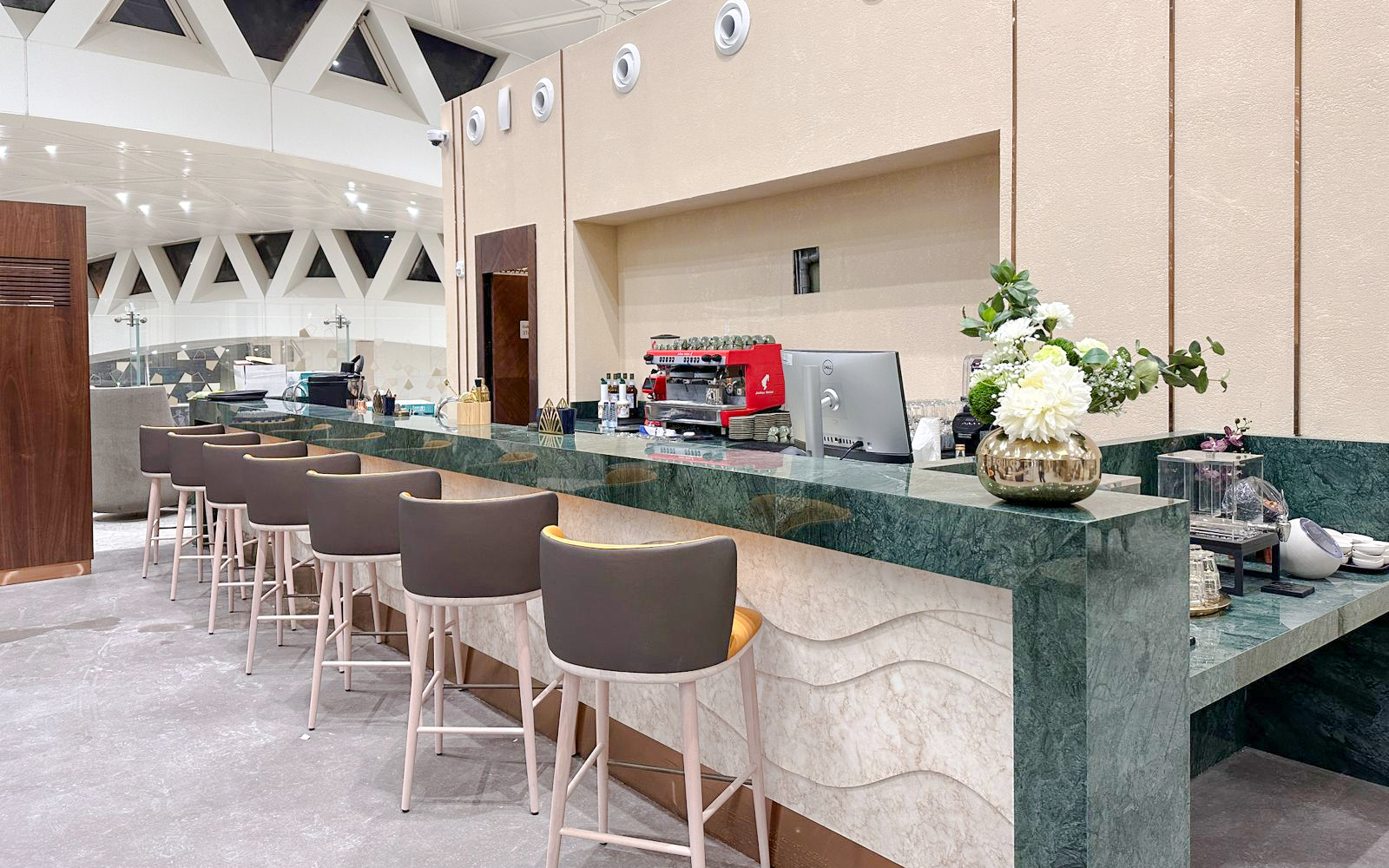 Cafe counter at Plaza Premium Lounge, Riyadh with seating and coffee machine.