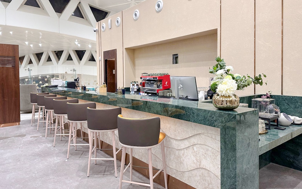 Cafe counter at Plaza Premium Lounge, Riyadh with seating and coffee machine.