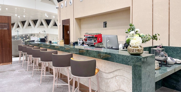 Cafe counter at Plaza Premium Lounge, Riyadh with seating and coffee machine.
