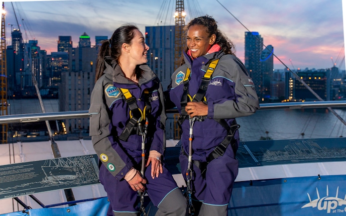 Guests enjoying the O2 rooftop experience at twilight with city skyline in the background.