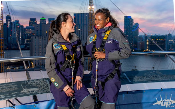 Guests enjoying the O2 rooftop experience at twilight with city skyline in the background.