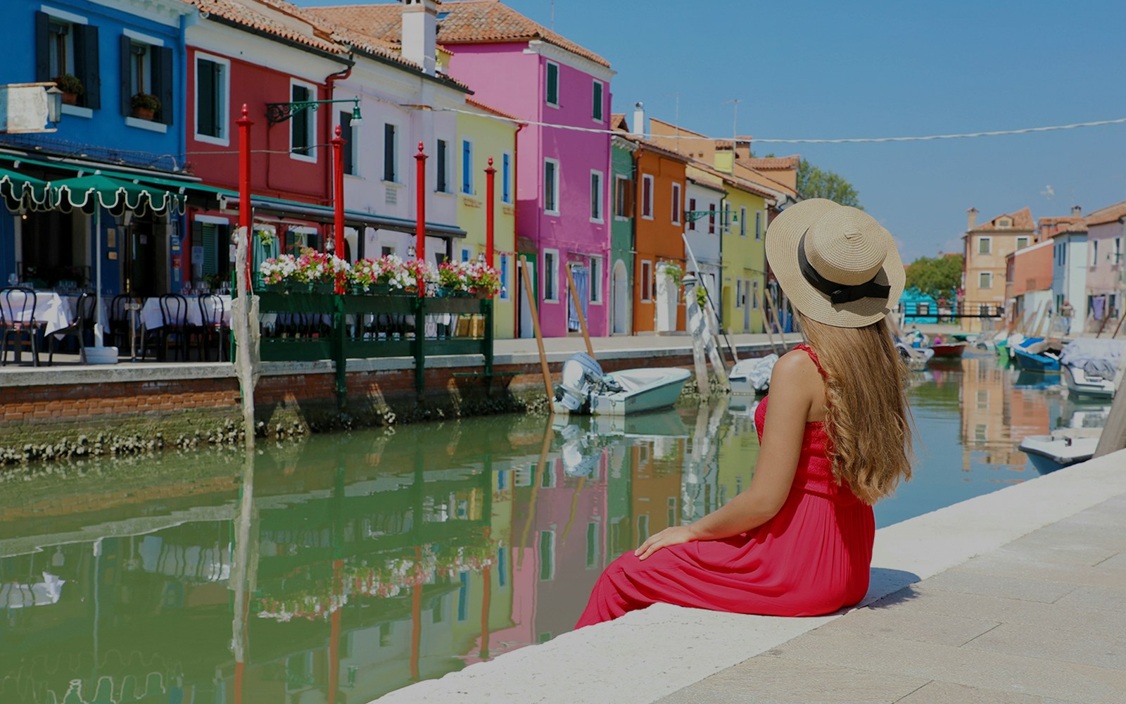 Girl viewing colorful buildings along Burano canal, Italy.