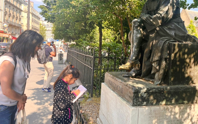 Child and adult exploring Montaigne statue during Treasure Hunt tour in Paris.