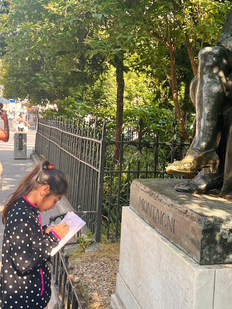 Child and adult exploring Montaigne statue during Treasure Hunt tour in Paris.