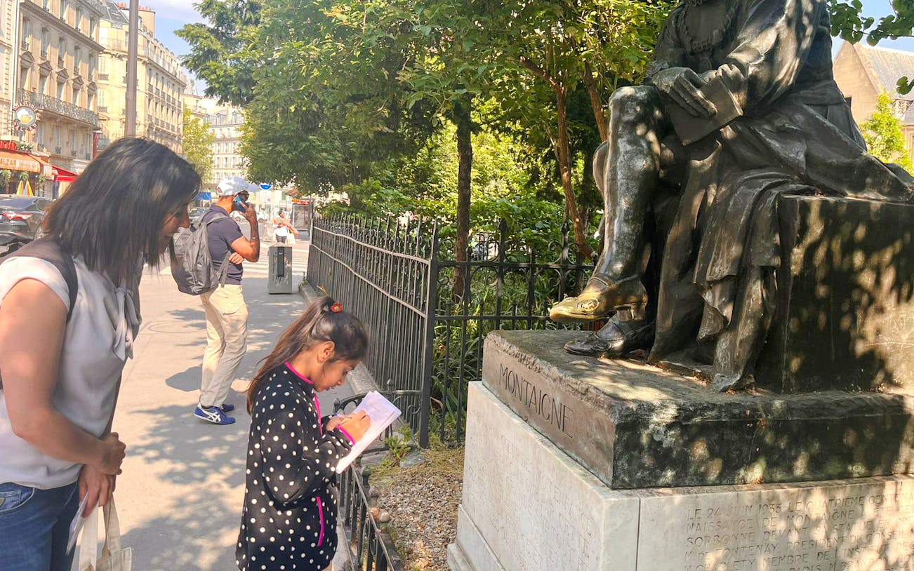 Child and adult exploring Montaigne statue during Treasure Hunt tour in Paris.