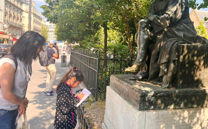 Child and adult exploring Montaigne statue during Treasure Hunt tour in Paris.