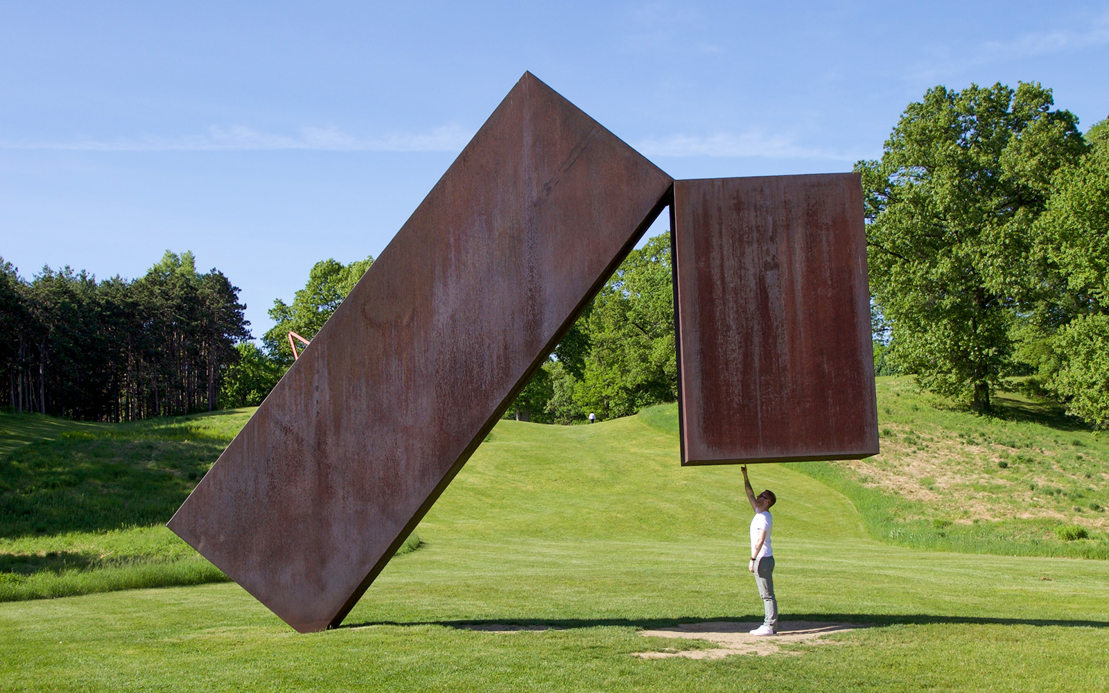 Person interacting with large steel sculpture at Storm King Art Center.