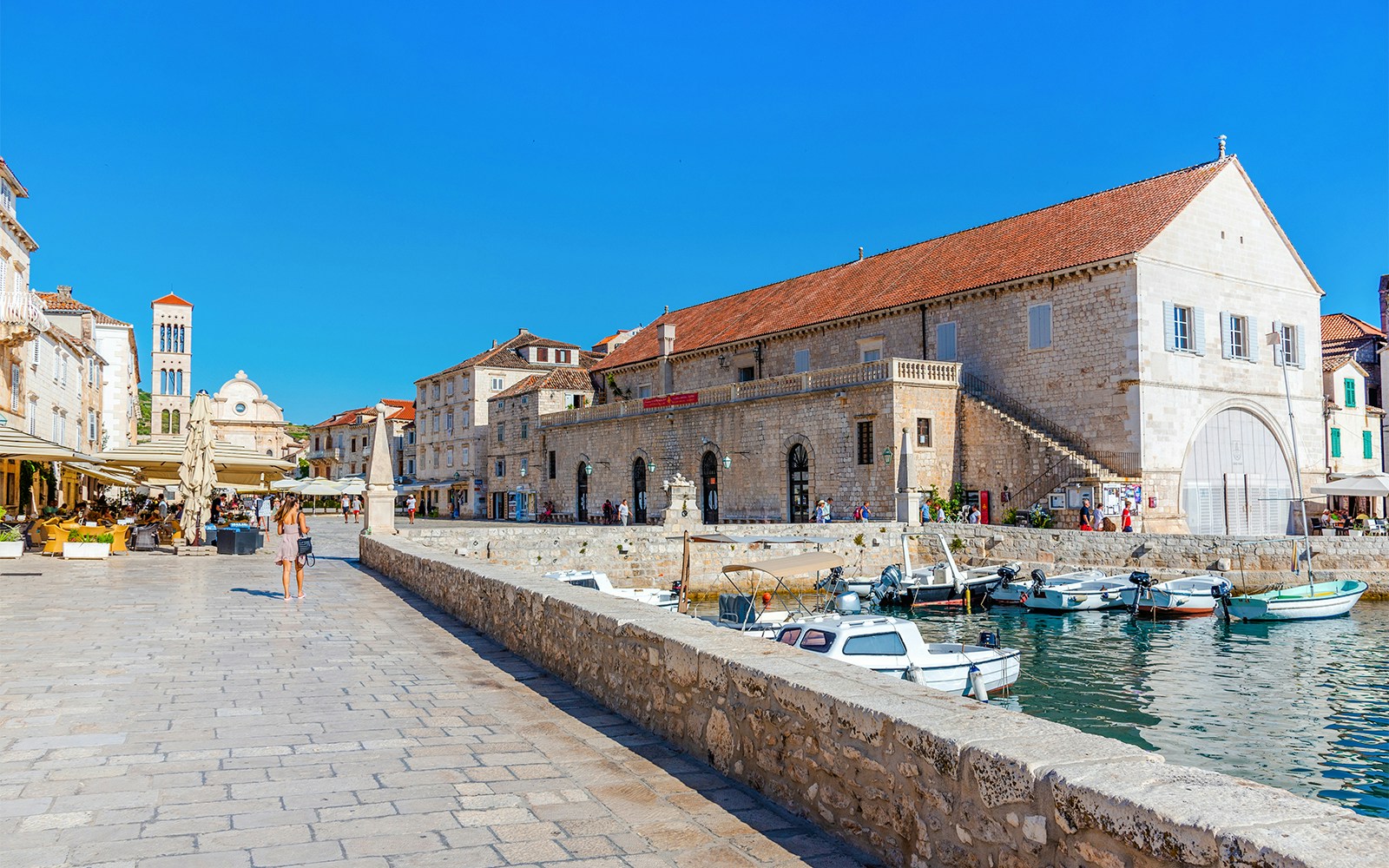 Arsenal in Hvar with boats docked, Cathedral of Saint Stephen in background, Croatia.