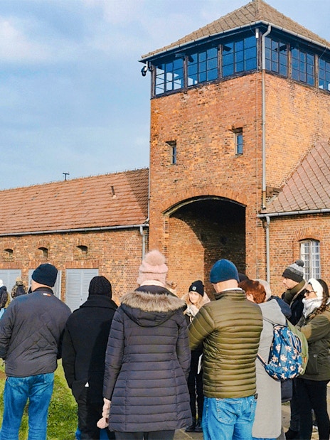 Group of tourists at the entrance gate of Auschwitz II during a guided tour.