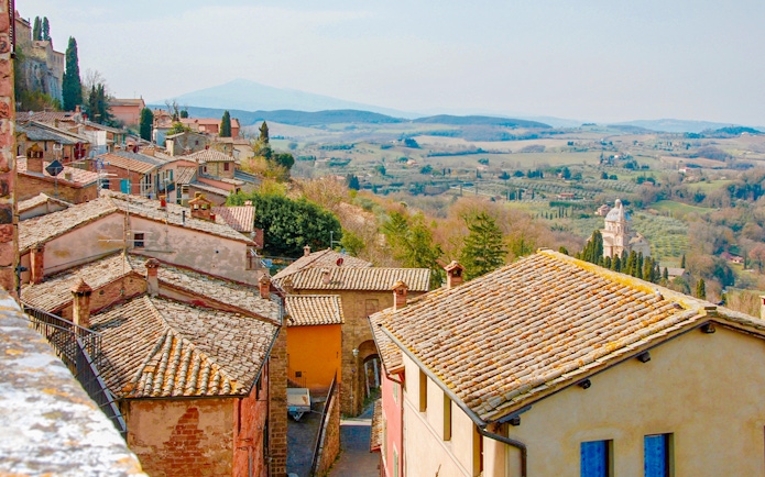 Tuscany countryside view with rustic rooftops and distant rolling hills.