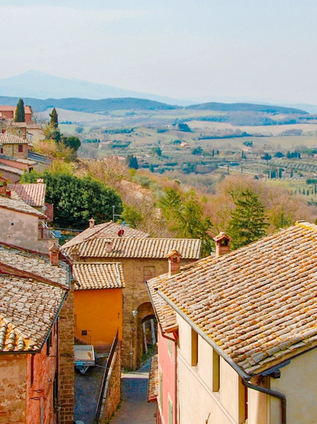 Tuscany countryside view with rustic rooftops and distant rolling hills.