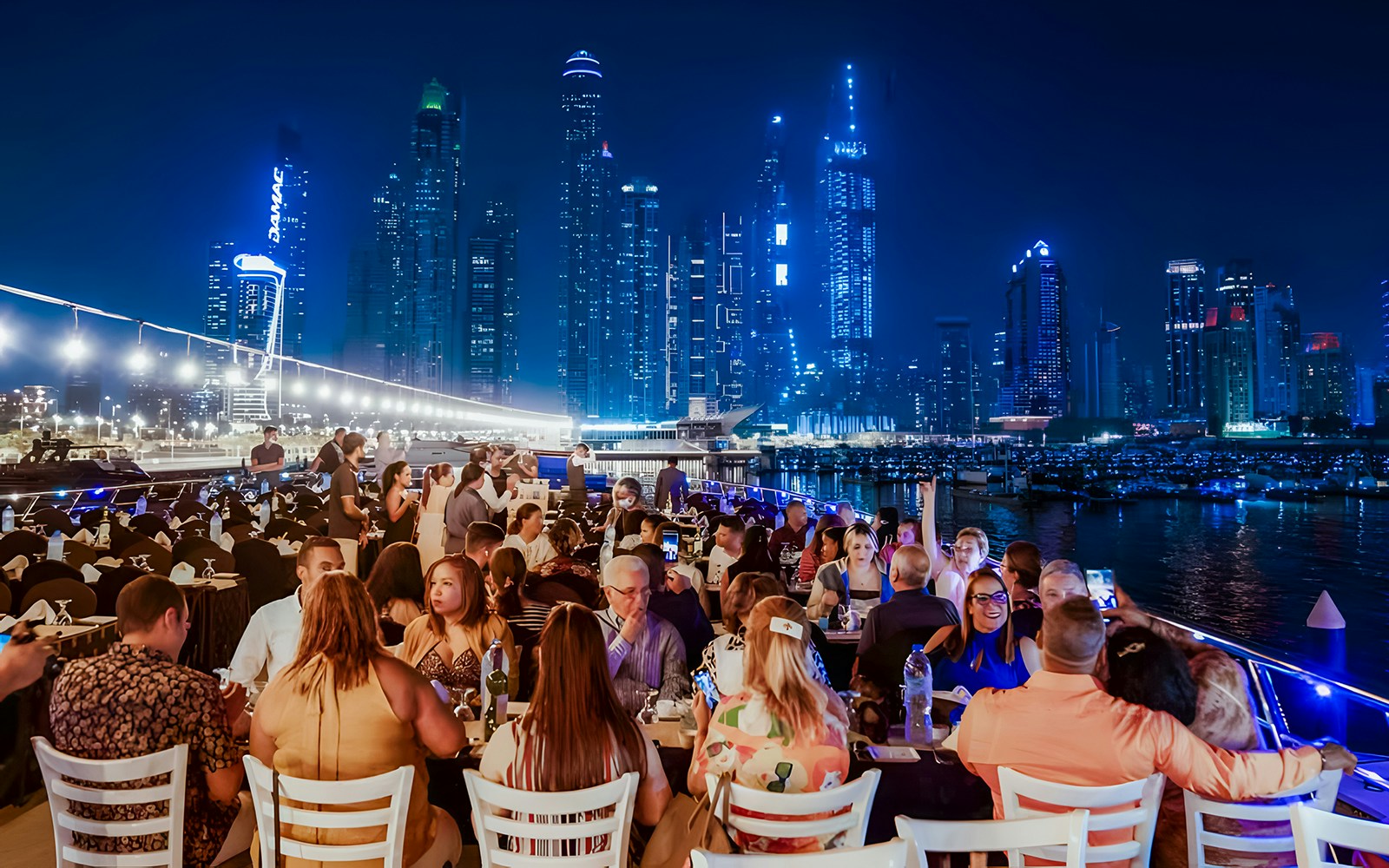 Dubai Marina luxury dhow dinner cruise with guests dining and enjoying entertainment.