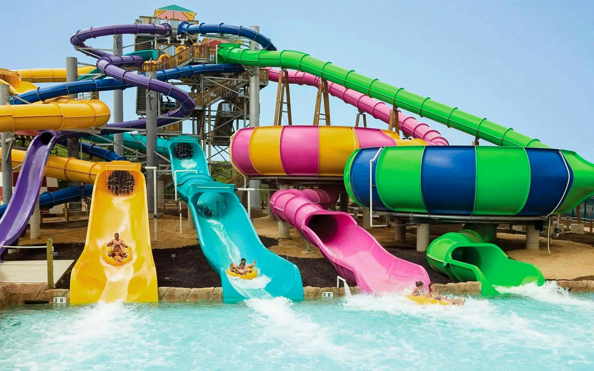 Water slides at Hurricane Harbor Chicago with people splashing into the pool.