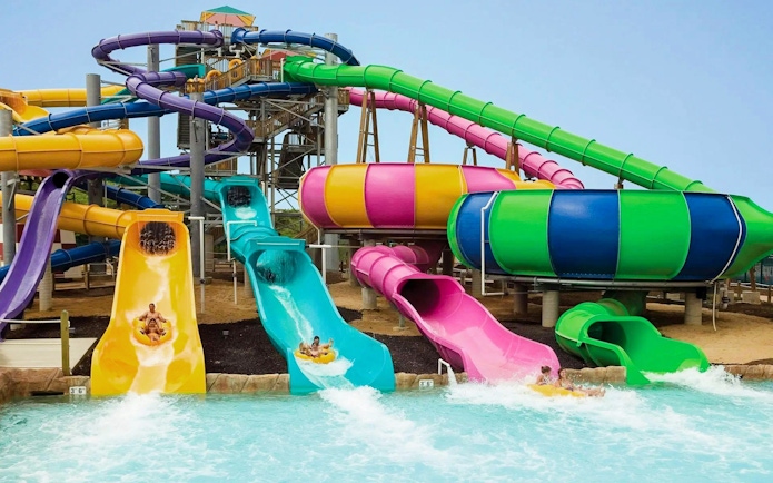 Water slides at Hurricane Harbor Chicago with people splashing into the pool.