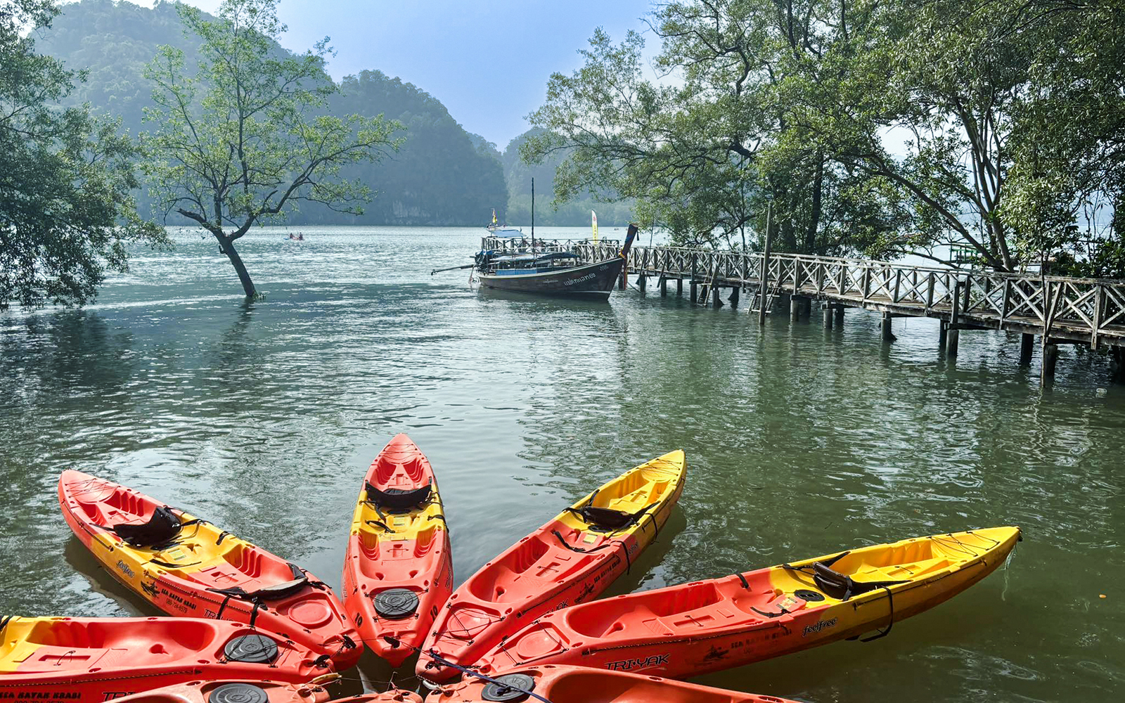 Kayaks on the water near a wooden pier in Ao Thalane, surrounded by mangrove forests.