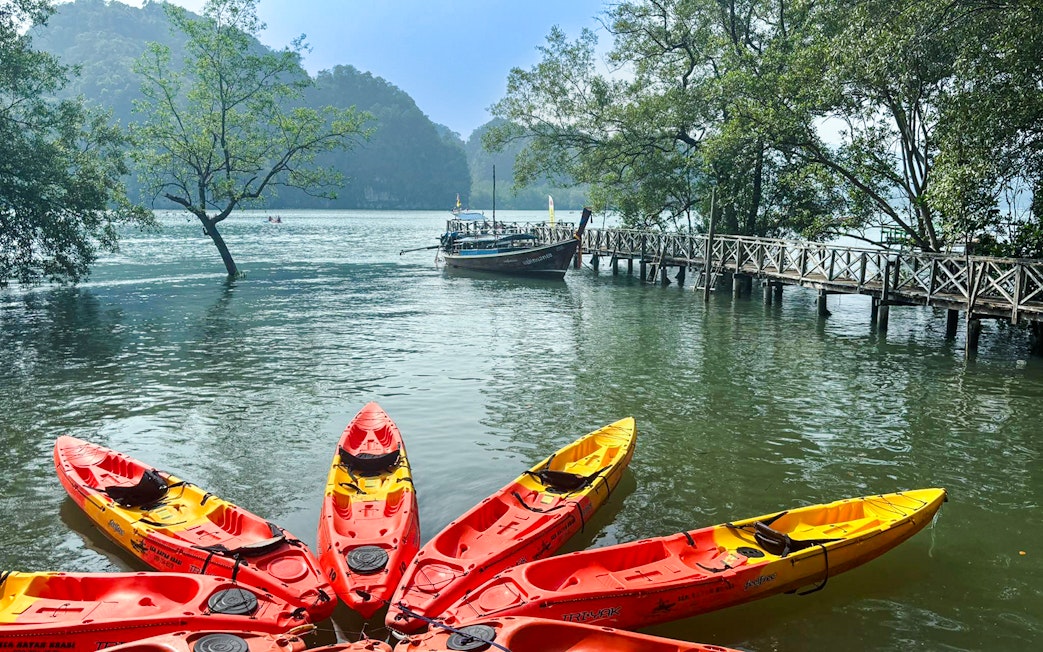 Kayaks on the water near a wooden pier in Ao Thalane, surrounded by mangrove forests.