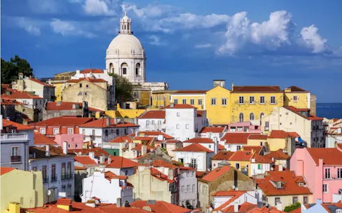 Lisbon's Alfama district with colorful rooftops and the National Pantheon in the background.