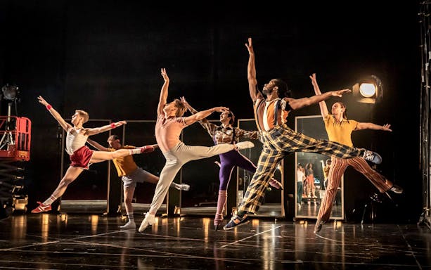 Dancers performing a high-energy routine in "A Chorus Line" on stage.